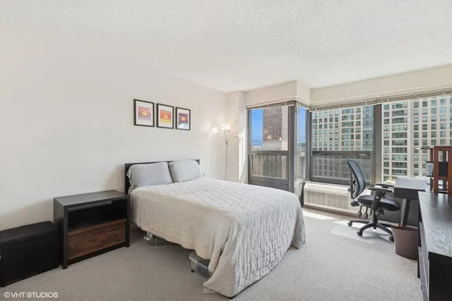 a bedroom with a bed a table and a large window