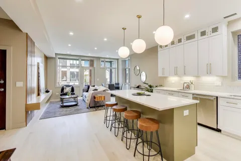 a large kitchen with a counter space a sink appliances and living room view