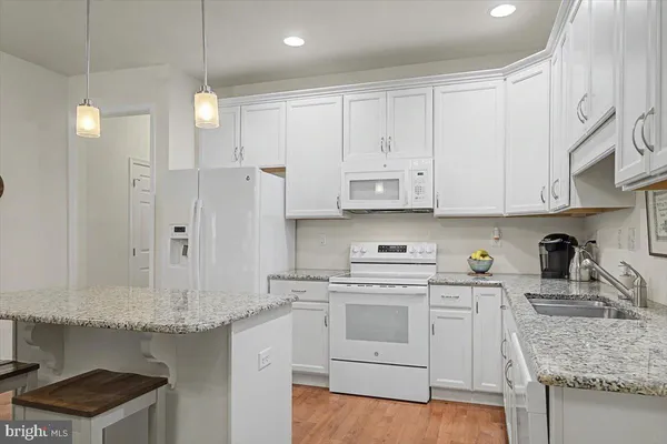 a kitchen with granite countertop white cabinets and white appliances