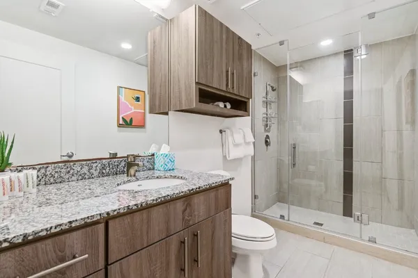 a bathroom with a granite countertop sink a toilet and shower