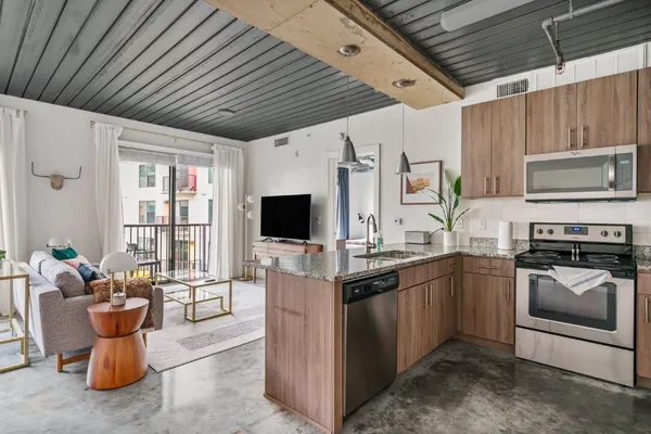 a kitchen with stainless steel appliances granite countertop a sink dishwasher stove and microwave with wooden floor