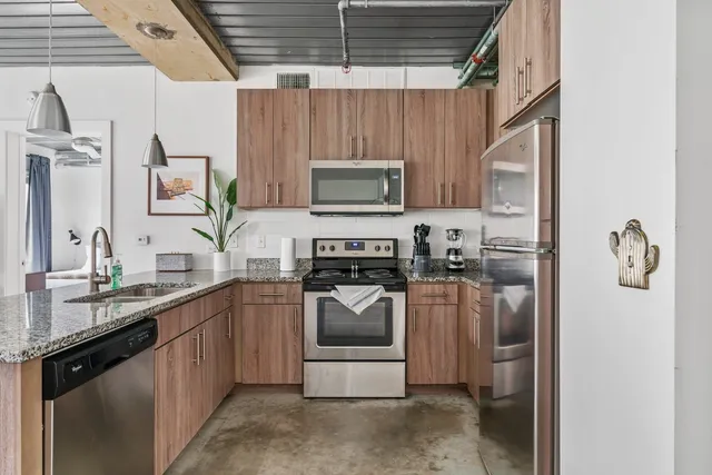 a kitchen with stainless steel appliances granite countertop a sink a stove and a refrigerator