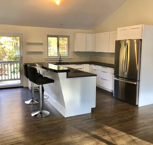 a kitchen with granite countertop a refrigerator a stove a sink cabinets and wooden floor