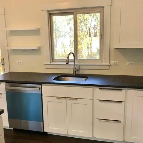 a kitchen with white cabinets and a window