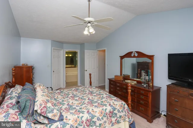 a bedroom with a bed and a flat tv screen on dresser
