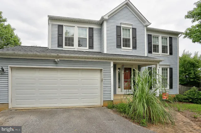 a view of a house with small yard plants and large tree