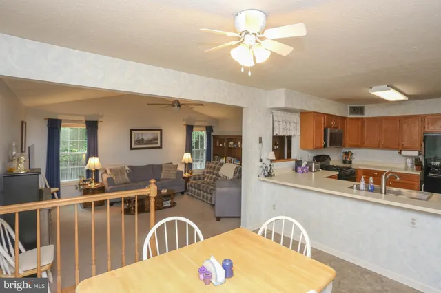 a kitchen with stainless steel appliances granite countertop a stove a sink a dining table and chairs with wooden floor