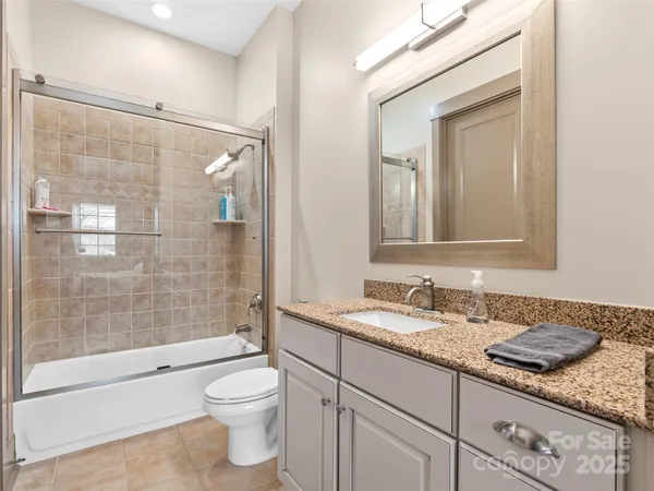 a bathroom with a granite countertop toilet sink and mirror