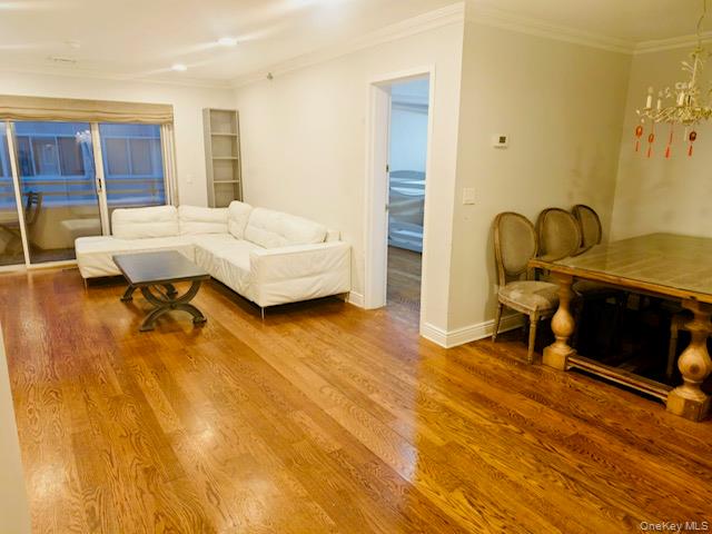 100 Cutter Mill Road, Unit 4G Great Neck, NY 11021 - Photo 5 of 18 Living room featuring crown molding, wood finished floors, and a chandelier