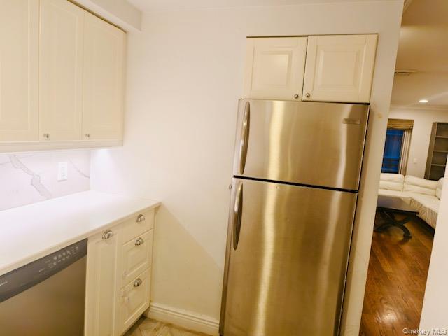 100 Cutter Mill Road, Unit 4G Great Neck, NY 11021 - Photo 8 of 18 Kitchen featuring stainless steel appliances, light countertops, white cabinets, and light wood finished floors
