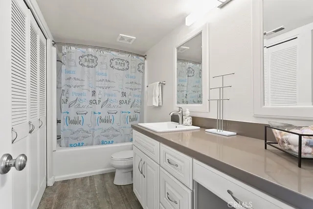 a spacious bathroom with a granite countertop sink a toilet a mirror a vanity and shower