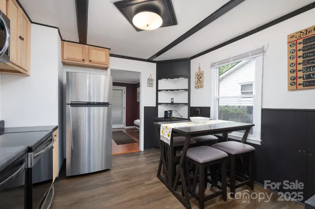 a kitchen with stainless steel appliances granite countertop a table chairs and a refrigerator