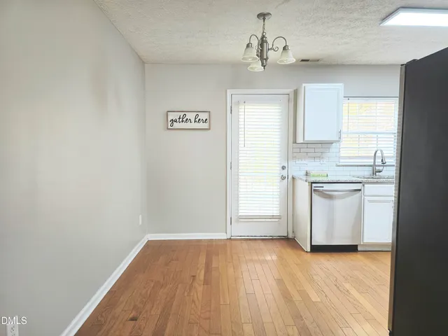 a view of a kitchen with white cabinets and wooden floor