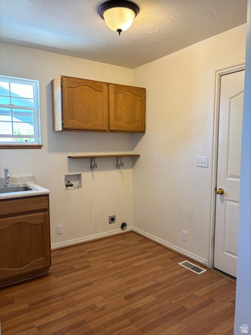 798 South 600 East Payson, UT 84651 - Photo 18 of 31 Laundry area featuring wood-finish flooring, a utility sink with base cabinetry, wall-mounted upper cabinetry, and a ceiling-mounted light fixture