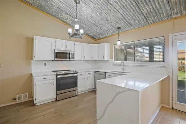 a kitchen with stainless steel appliances granite countertop a sink a stove top oven and white cabinets