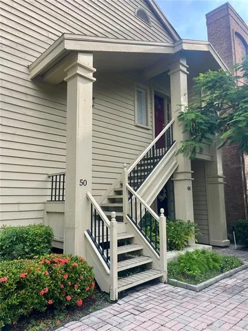 a view of a house with wooden stairs and a small yard