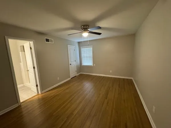 an empty room with wooden floor chandelier fan and windows