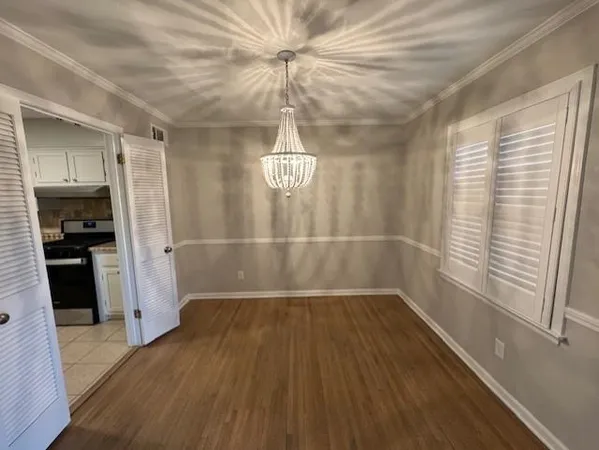 a view of a hallway with wooden floor and a chandelier