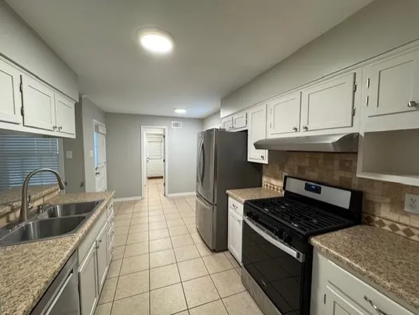 a kitchen with granite countertop a stove sink and cabinets