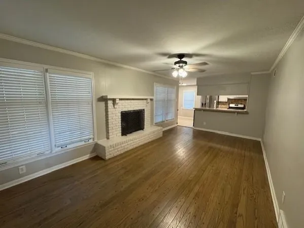 an empty room with wooden floor fireplace and windows