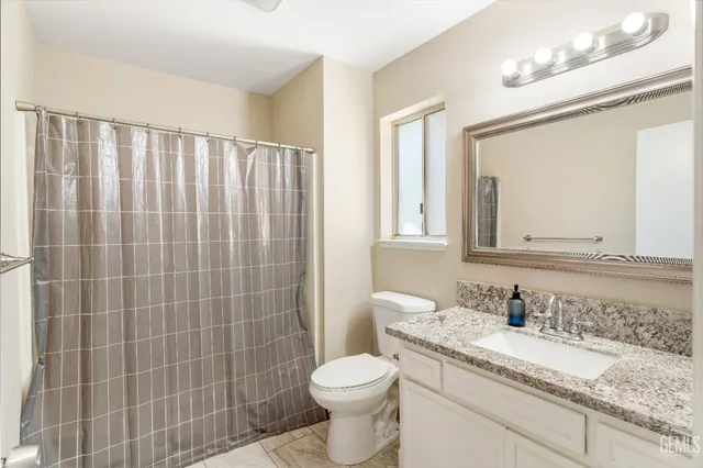a bathroom with a granite countertop sink toilet and shower