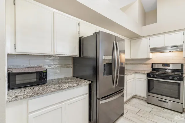 a kitchen with granite countertop a refrigerator stove and microwave