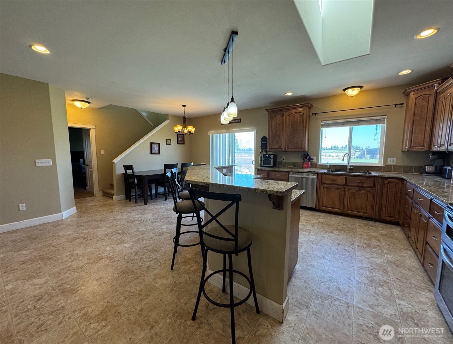 849 South McKinney Road Othello, WA 99344 - Photo 10 of 39 a kitchen with stainless steel appliances granite countertop a stove a sink dishwasher a dining table and chairs with wooden floor