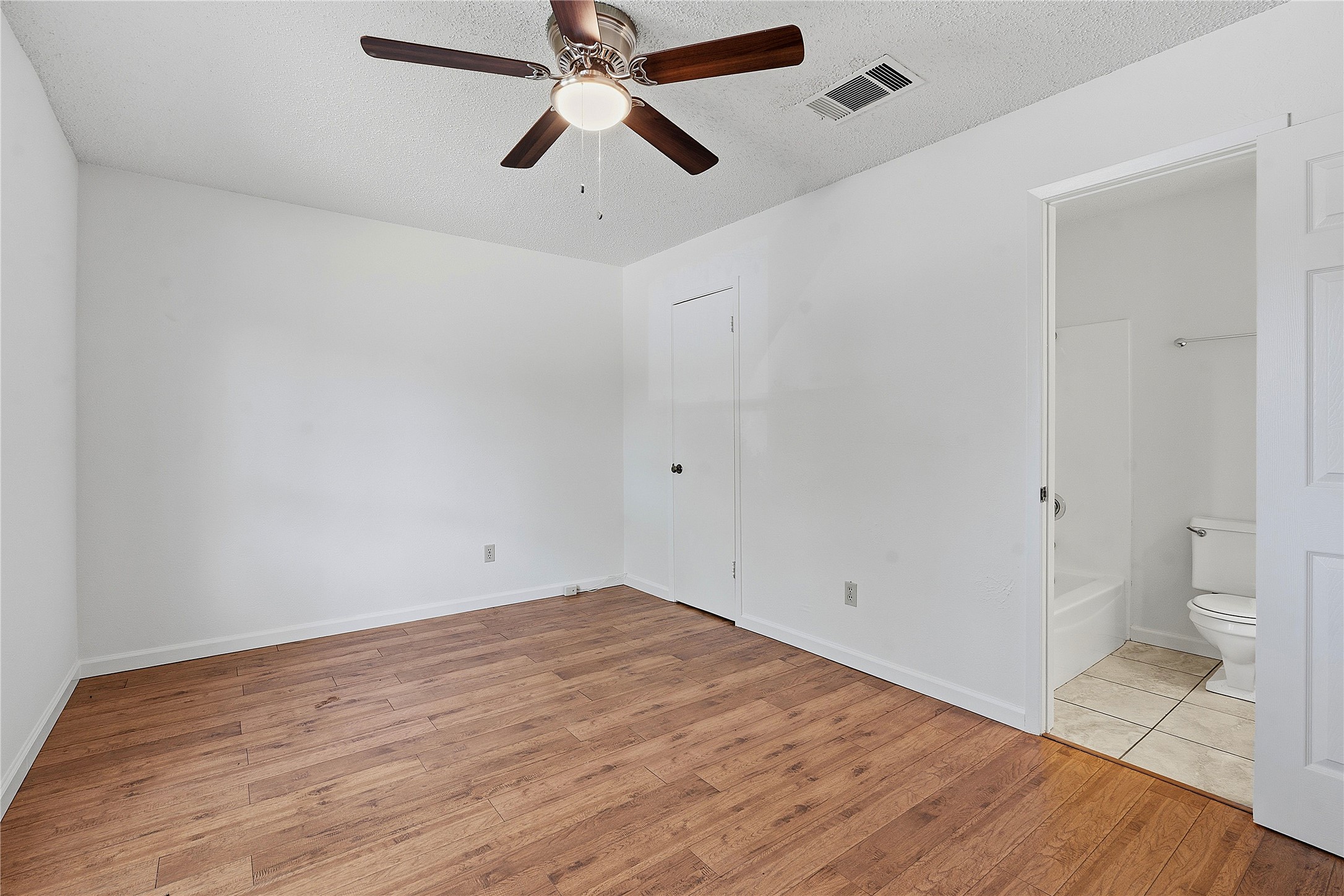 6205 Shadow Bend Austin, TX 78745 - Photo 12 of 31 Laminate flooring throughout this cozy room, featuring a ceiling fan and direct bathroom access.
