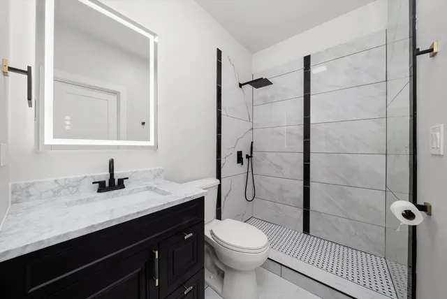 a bathroom with a granite countertop sink toilet and shower