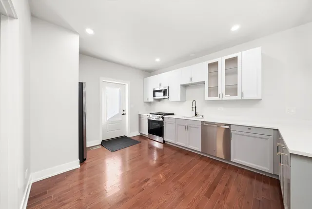 a large white kitchen with stainless steel appliances granite countertop a sink and wooden floor