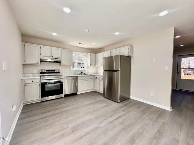a kitchen with a refrigerator and a stove top oven