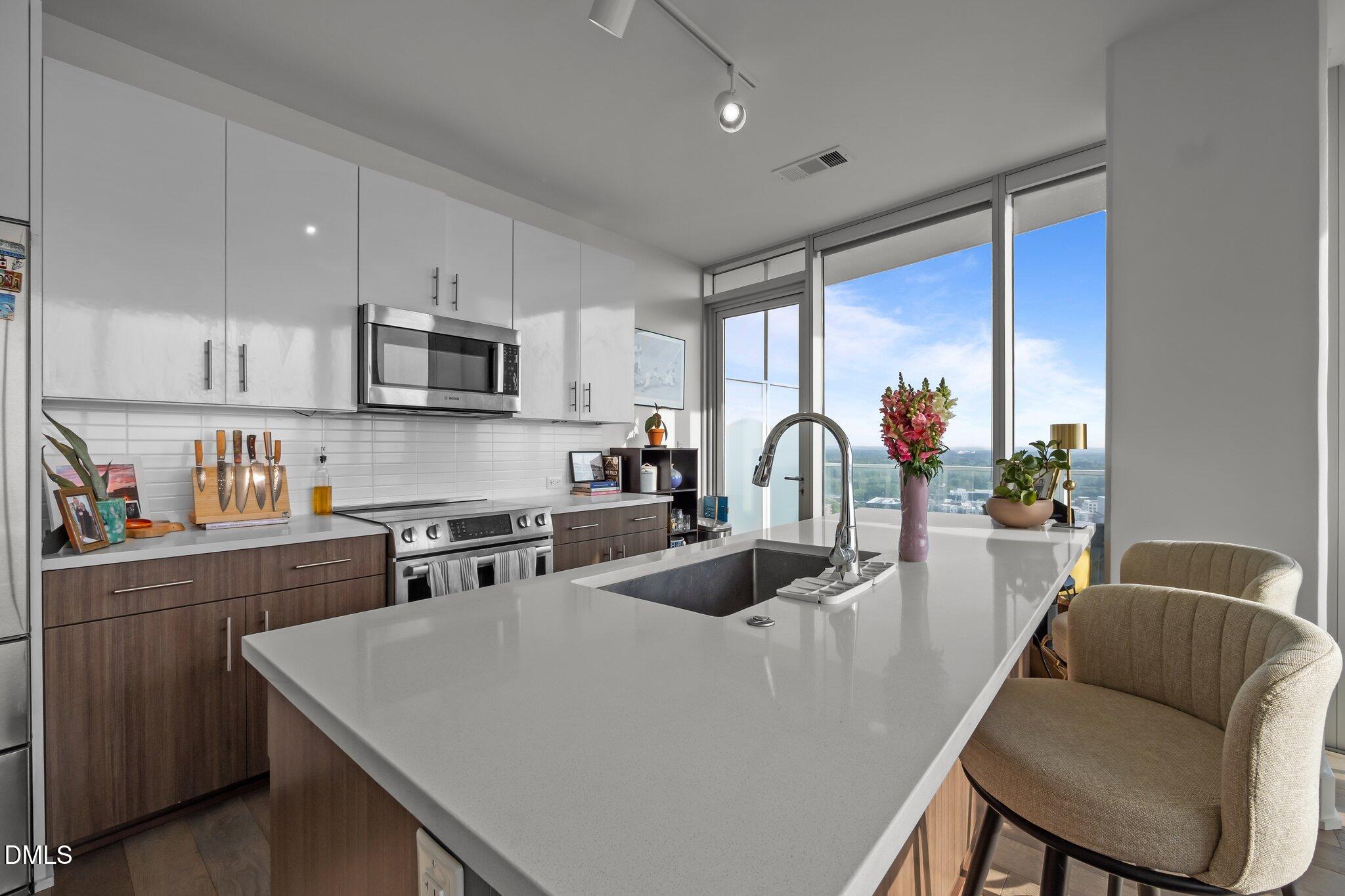 110 Corcoran Street, Unit 2101 Durham, NC 27701 - Photo 10 of 23 a kitchen with stainless steel appliances granite countertop a sink a stove and a refrigerator