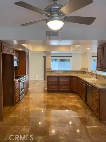 a large kitchen with kitchen island a counter space a sink and stainless steel appliances