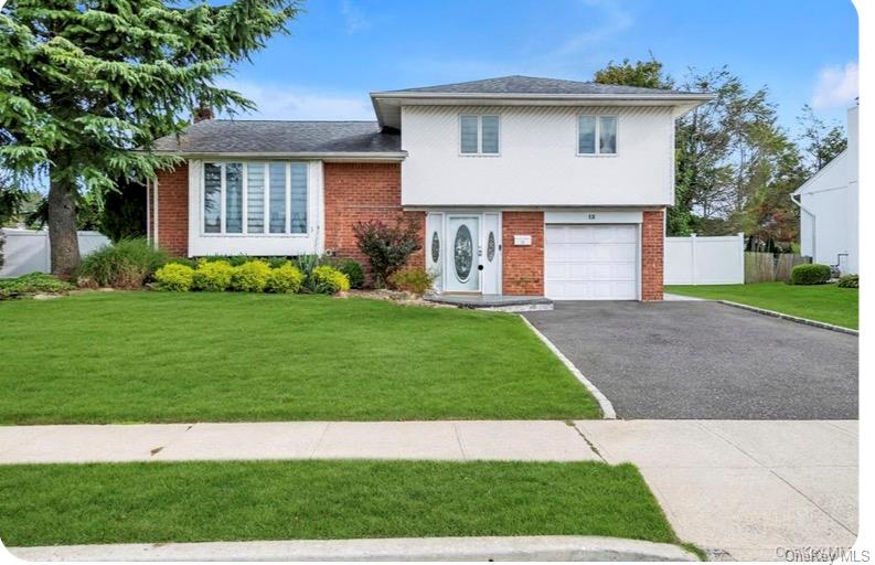 Tri-level home with brick siding, a garage, asphalt driveway, and a shingled roof