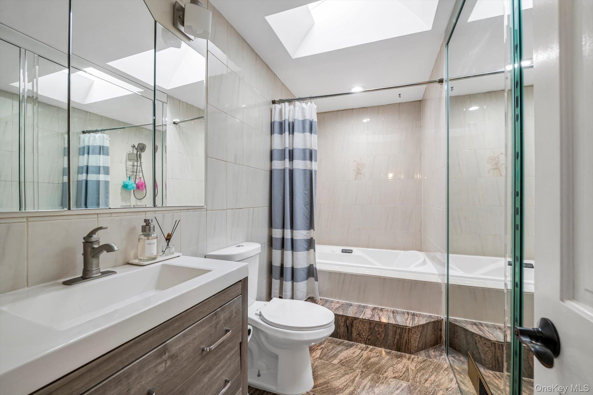 12 Julliard Drive Plainview, NY 11803 - Photo 13 of 23 Full bath with tile walls, tiled shower / bath combo, a skylight, and vanity