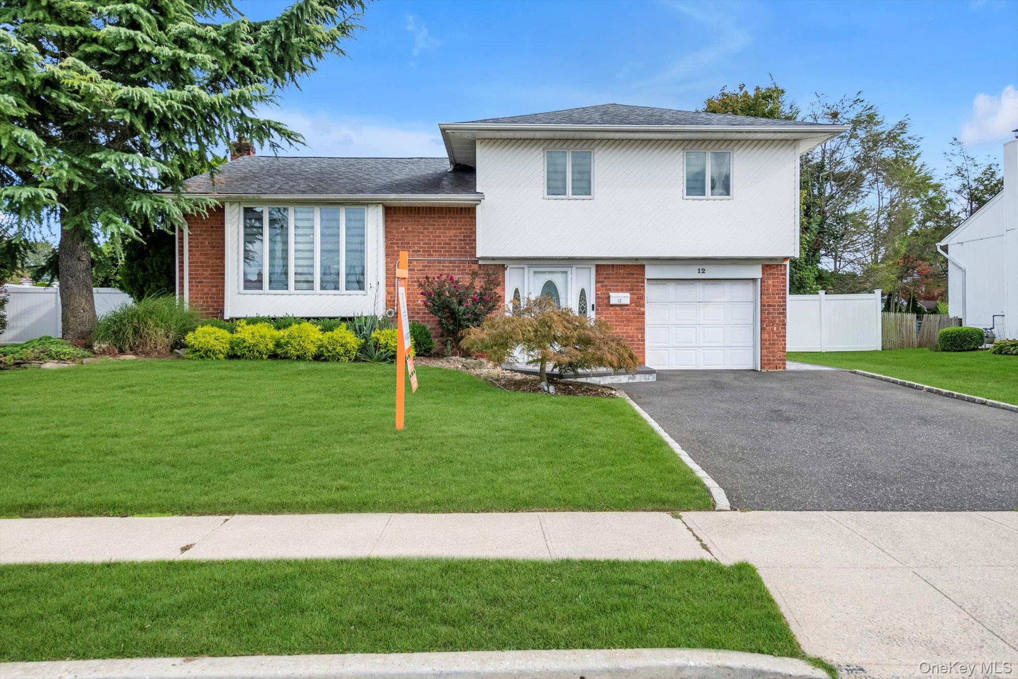 12 Julliard Drive Plainview, NY 11803 - Photo 2 of 23 Split level home featuring brick siding, asphalt driveway, a garage, a shingled roof, and a chimney