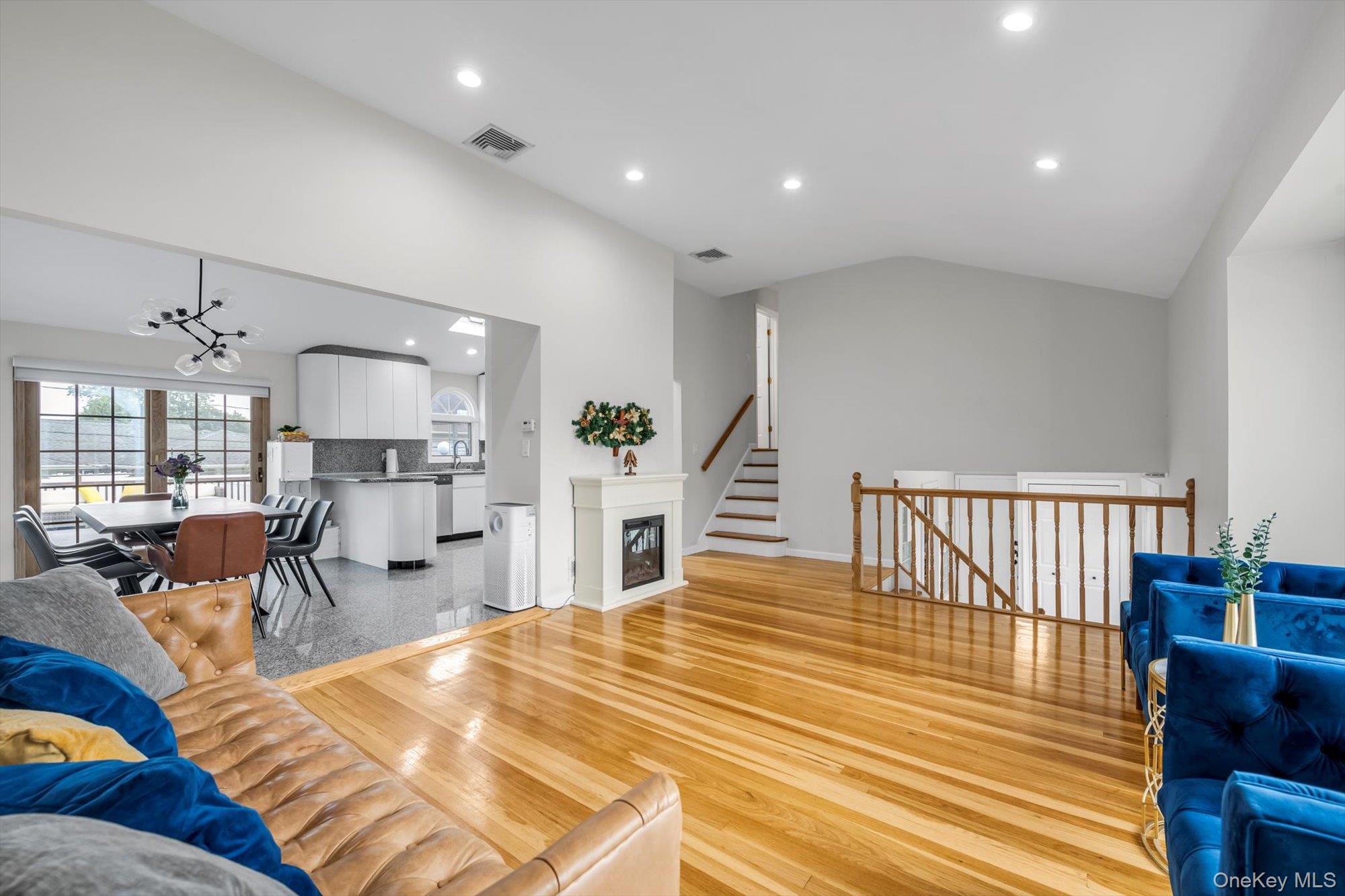 12 Julliard Drive Plainview, NY 11803 - Photo 6 of 23 Living area with recessed lighting, a chandelier, light wood-style floors, lofted ceiling, and stairway