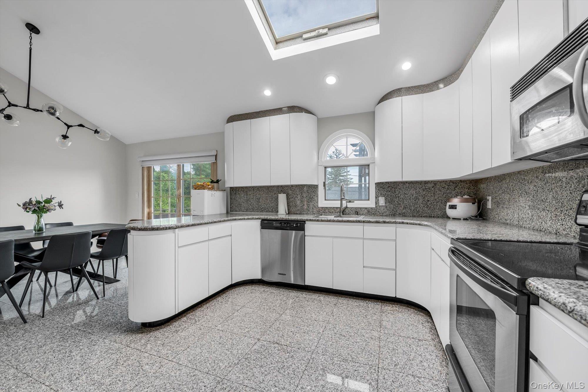 12 Julliard Drive Plainview, NY 11803 - Photo 8 of 23 Kitchen featuring stainless steel appliances, tasteful backsplash, white cabinets, a peninsula, and healthy amount of natural light