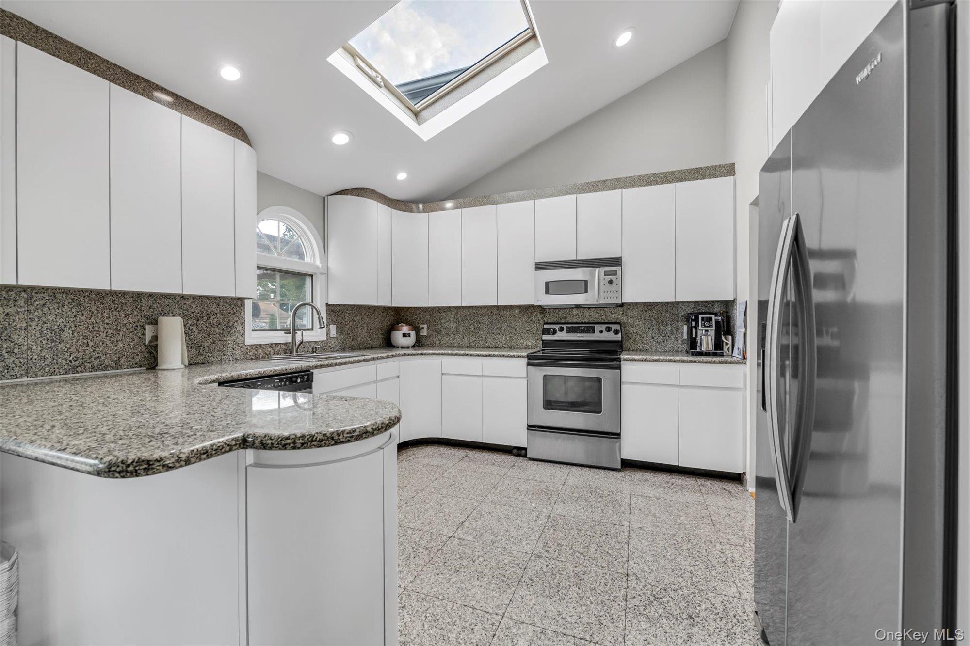 12 Julliard Drive Plainview, NY 11803 - Photo 9 of 23 Kitchen with vaulted ceiling, appliances with stainless steel finishes, a peninsula, backsplash, and a skylight