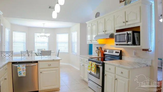 a kitchen with stainless steel appliances granite countertop a stove a sink and a microwave