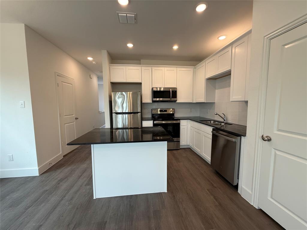 412 East 7th Street, Unit 2 Bonham, TX 75418 - Photo 7 of 20 a kitchen with kitchen island a refrigerator stove a sink and a oven with wooden floor