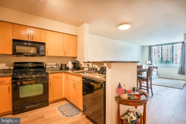 a kitchen with stainless steel appliances granite countertop a stove top oven a sink dishwasher a dining table and chairs with wooden floor