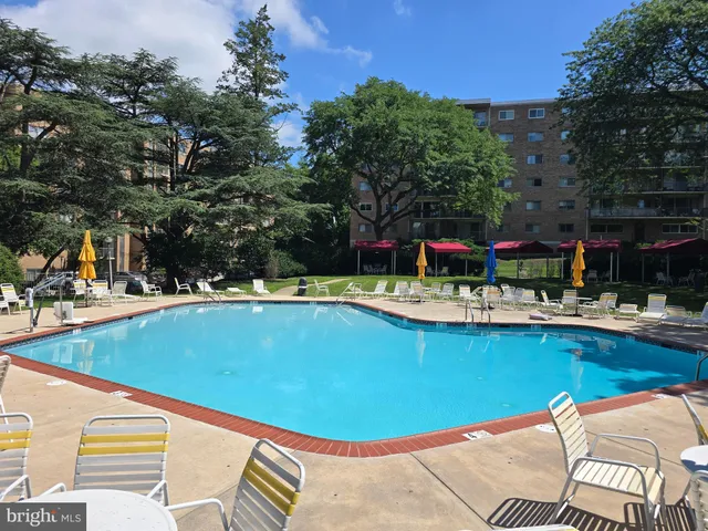 a view of a swimming pool with a table and chairs under an umbrella