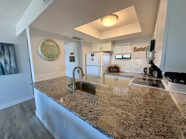 a kitchen with kitchen island granite countertop a sink a stove and cabinets
