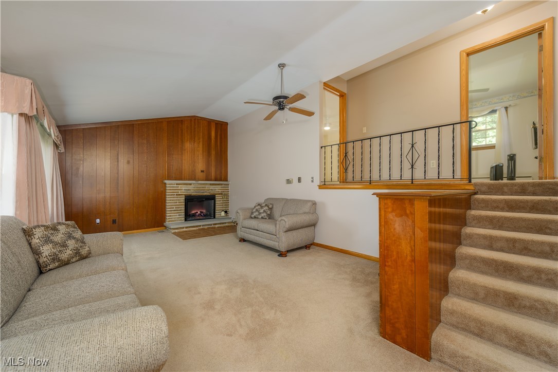 6571 Peck Road Ravenna, OH 44266 - Photo 8 of 44 Living room featuring ceiling fan, wood accent wall, vaulted ceiling with open staircase to the second floor