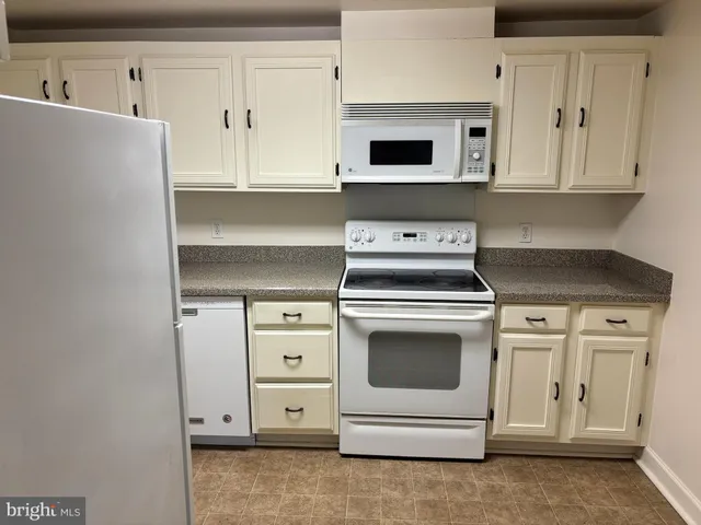 a kitchen with white cabinets and white appliances
