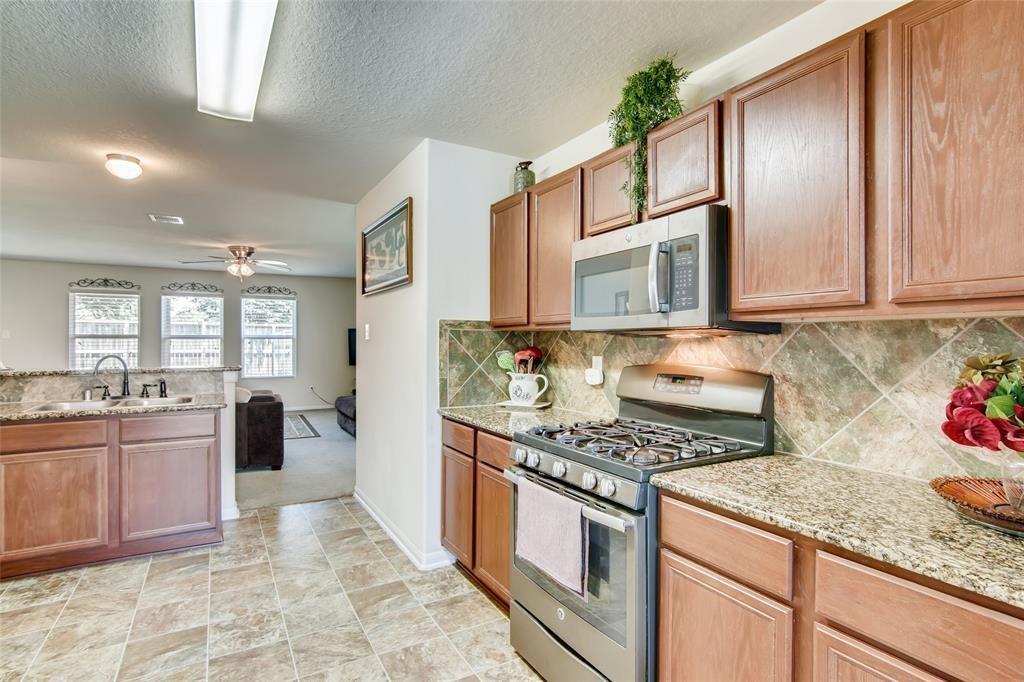 a kitchen with stainless steel appliances granite countertop a stove top oven a sink a refrigerator and cabinets
