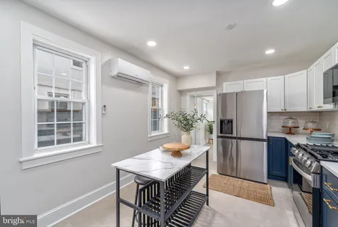 a kitchen with stainless steel appliances a dining table chairs refrigerator and cabinets