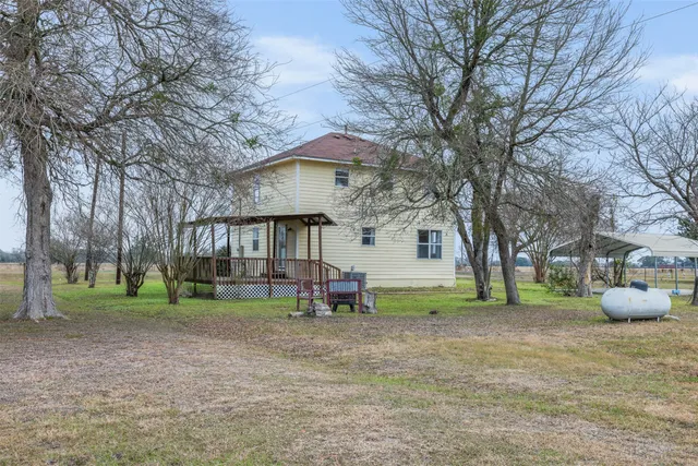 a view of house with a backyard and trees