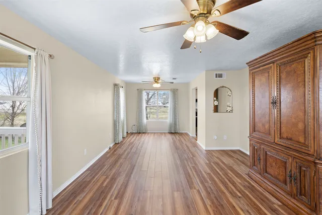 a view of a hallway with wooden floor and chandelier fan